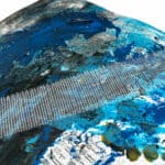 Abstract artwork featuring a mesh grid over a mixed media background with dominant blue tones and various textures. Small printed squares are visible at the bottom.